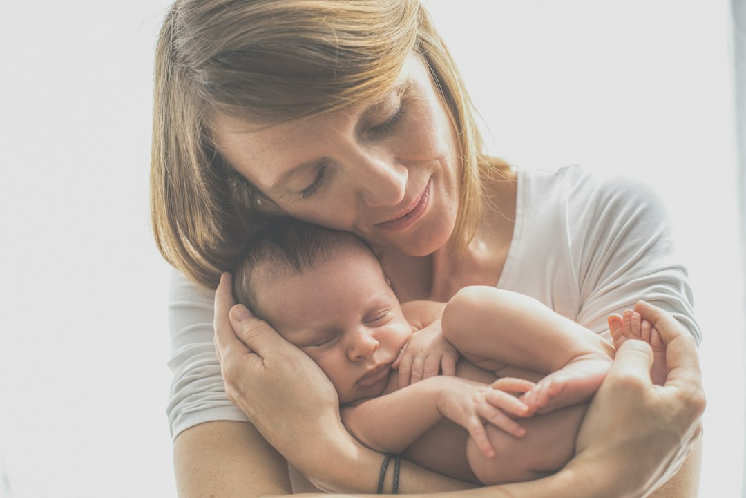 Mother holding her newborn baby at home